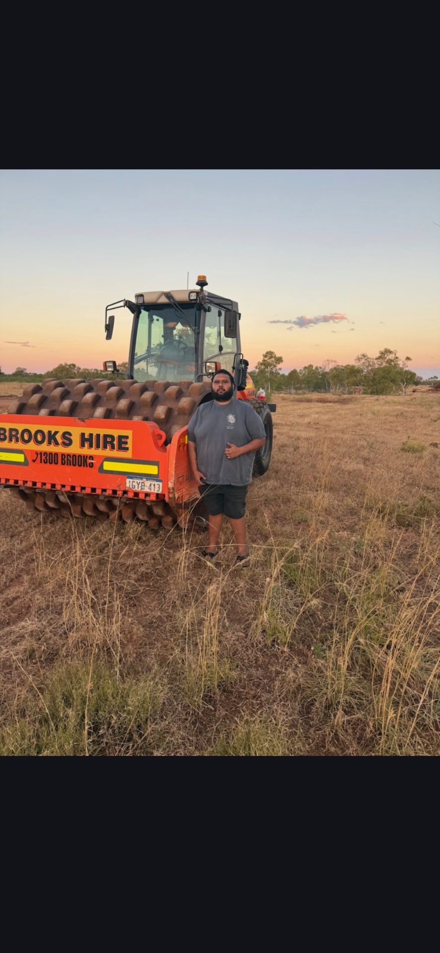 Trainer standing beside a padfoot compaction roller at sunset during civil training in the Northern Territory